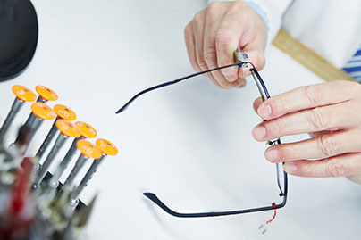 Hand eines Optikers repariert den Metallbacken einer Brille